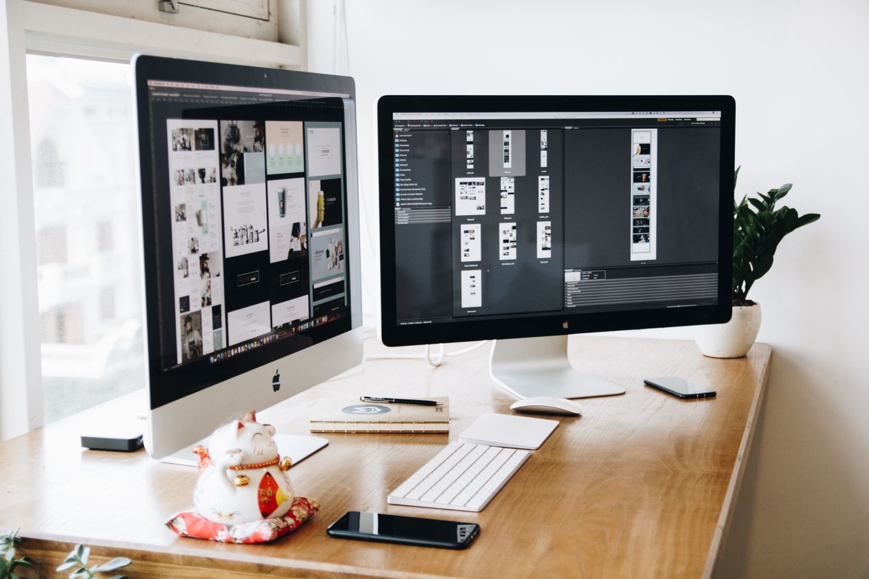 Graphic designer workspace with two monitors on a wooden desk, used to illustrate the free Inkvec AI logo vectorizer